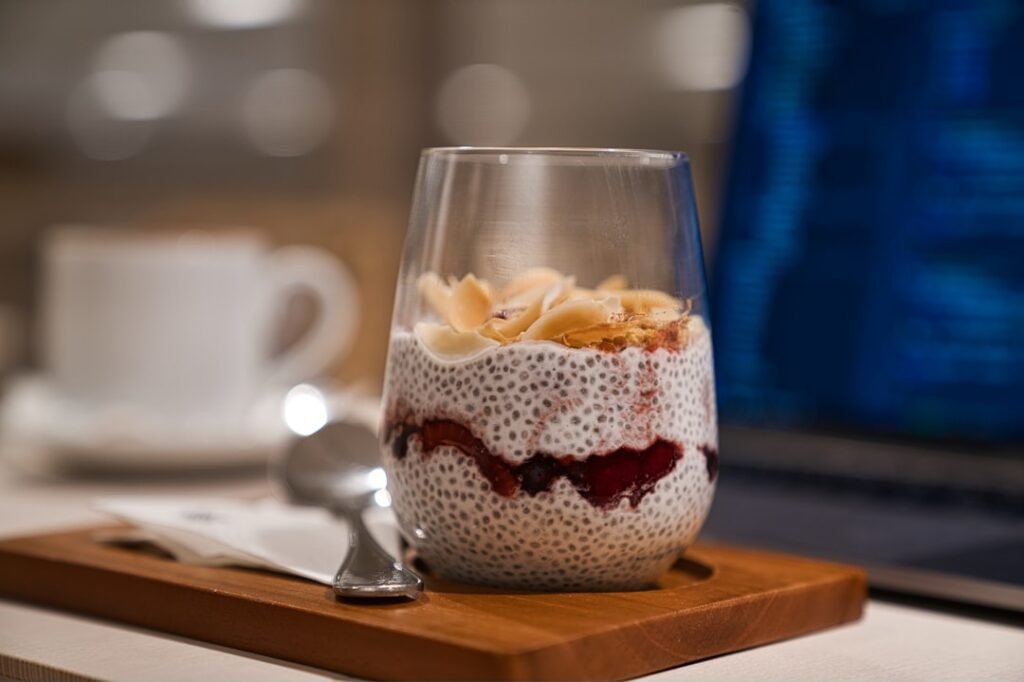 A spoonful of chia seeds and flaxseeds next to a bowl of yogurt