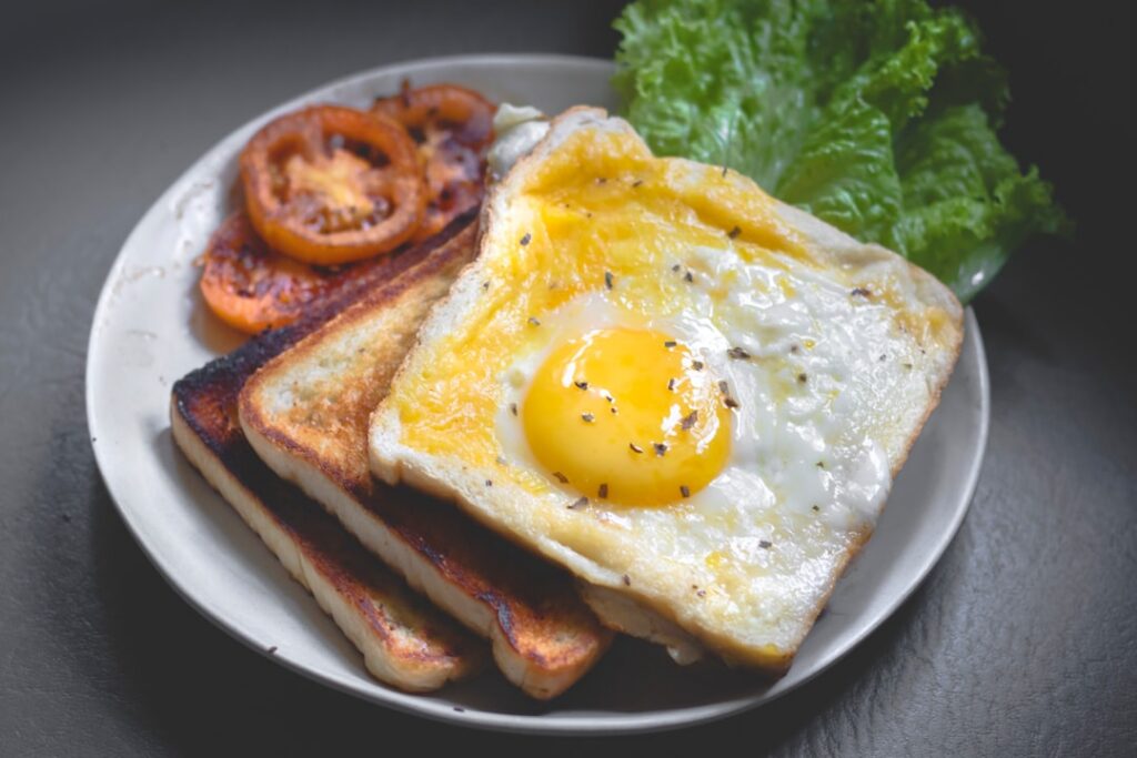 Two perfectly cooked fried eggs on a plate with some greens
