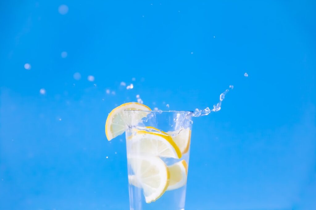A close-up of a steaming glass of water with a slice of lemon exuding warmth and comfort The background is softly blurre