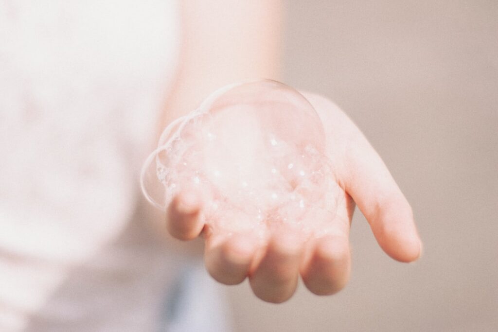 A close-up of hands gently mixing a small dollop of petroleum jelly with the liquid from a beauty-boosting nutrient caps