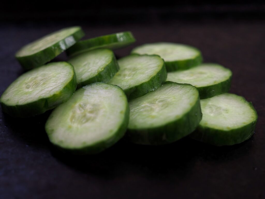 Close-up shot of sliced cucumbers and leafy green lettuce showing their fresh crisp texture and water content
