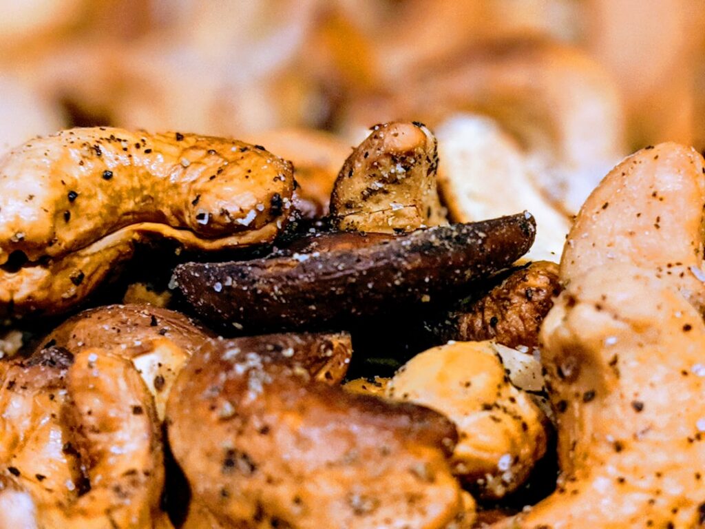 A close-up of roasted cashews in a wooden bowl perhaps with a sprinkle of salt or next to other healthy snacks
