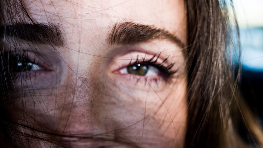 A woman smiling and looking refreshed highlighting her bright and revitalized under-eye area after consistent use of a n