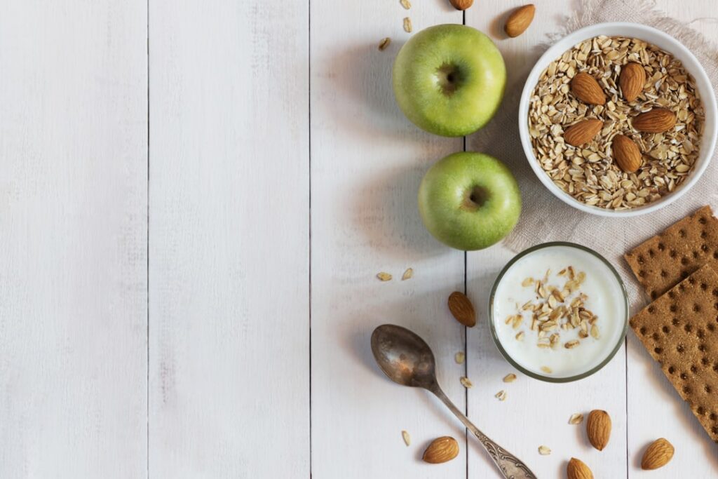 An overhead shot of various heart-healthy foods spread out on a wooden table including avocados berries leafy greens nut