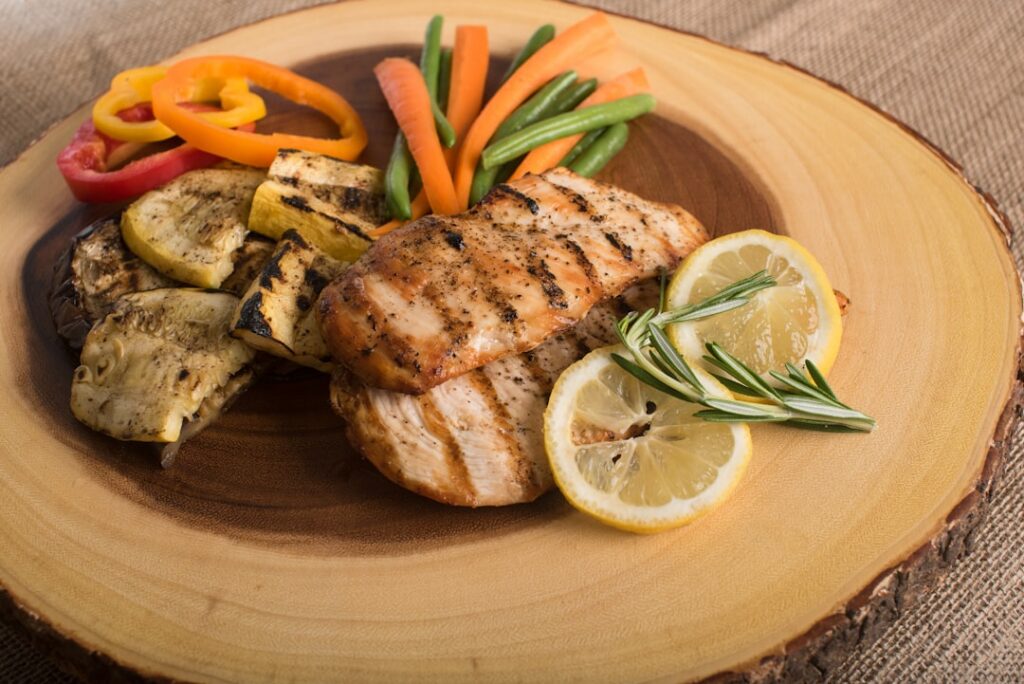 A perfectly grilled salmon fillet served with a side of fresh asparagus and lemon wedges on a white plate emphasizing a