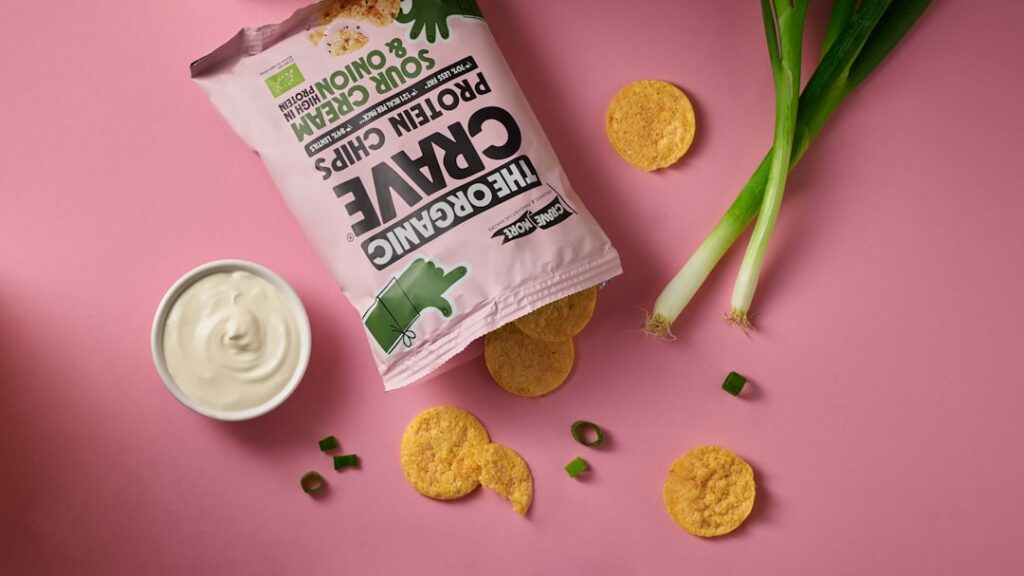 A vibrant creamy vegan chip dip in a stylish bowl garnished with fresh herbs surrounded by an assortment of colorful veg