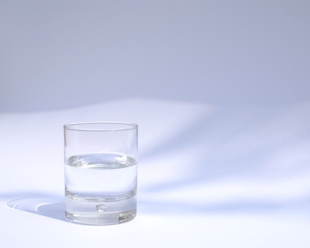 Four identical clear glasses each filled to the same water level but containing different objects one with scissors one 