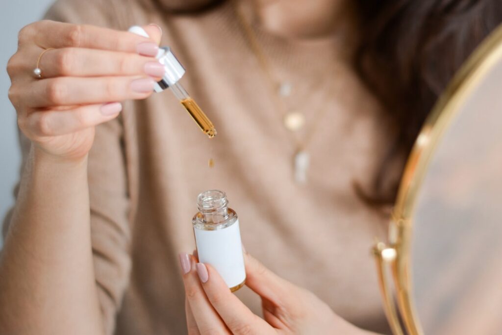 A person gently massaging a few drops of oil onto their face demonstrating proper application of a facial remedy