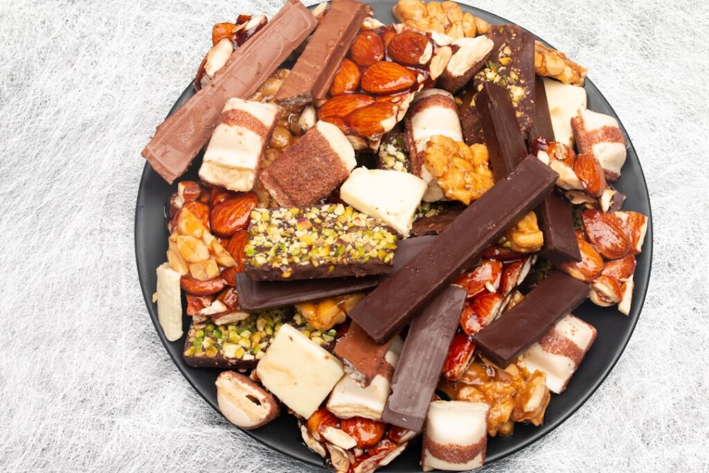 A hand reaching for one of several homemade stick snacks arranged artfully on a serving platter featuring various textur