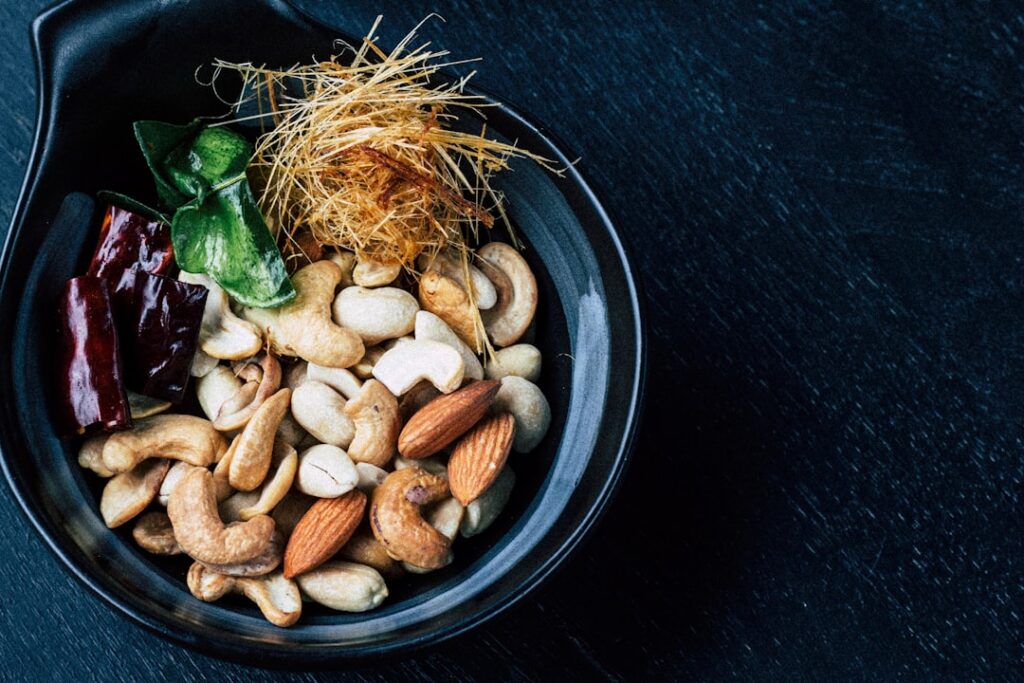 A vibrant close-up shot of a bowl of sliced or cubed mango pieces mixed with a variety of healthy nuts like almonds and 