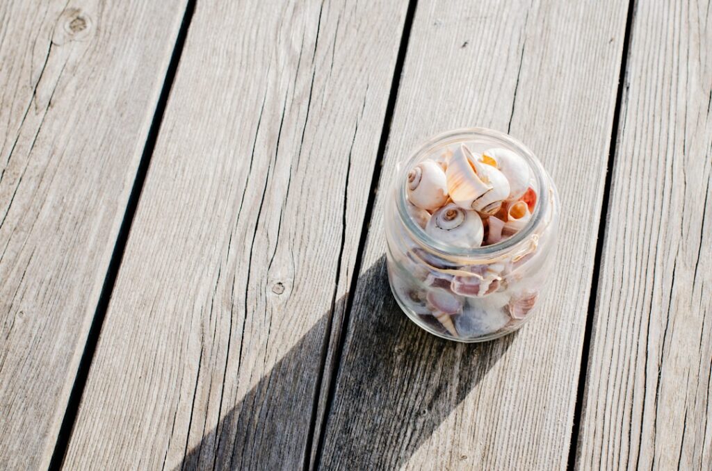 Glass jars filled with dark green purslane paste and ice cube trays with frozen green purslane cubes on a rustic wooden 