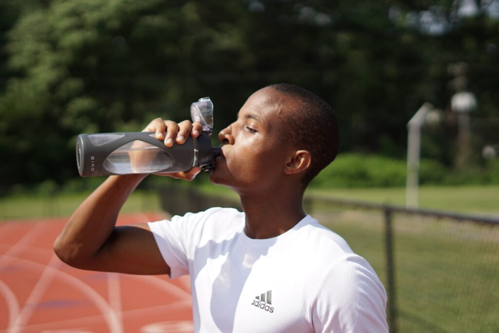 A person drinking water from a reusable bottle during a workout emphasizing hydration and consistent effort for weight l