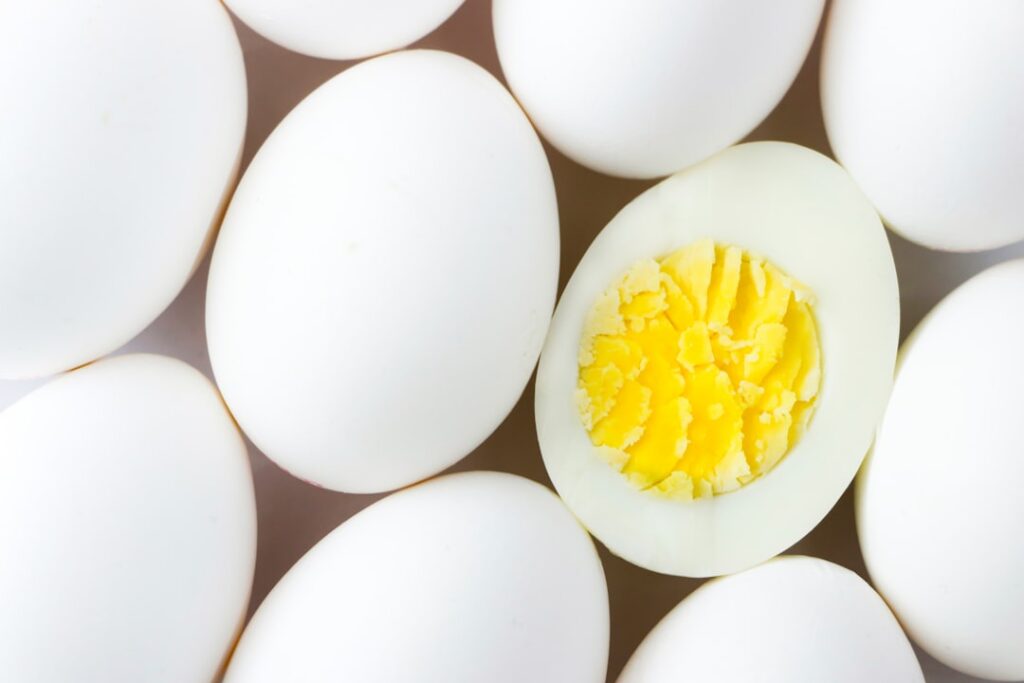 A bowl containing approximately 16-17 large hard-boiled eggs illustrating the quantity needed for 100g of protein
