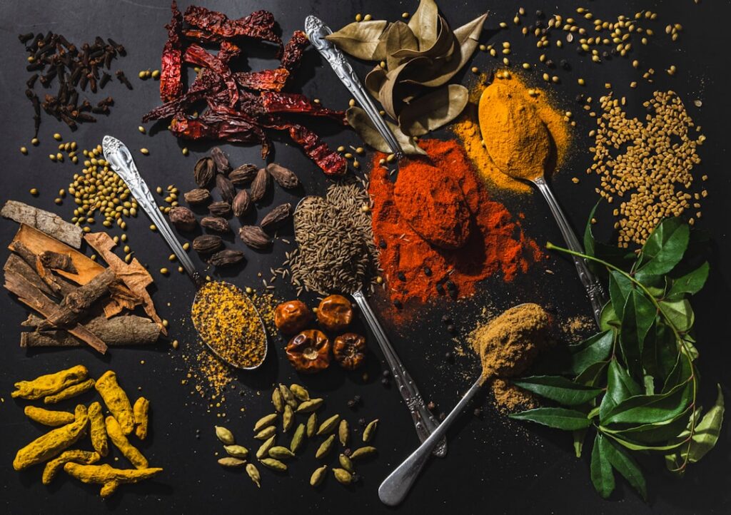 An array of colorful and fresh medicinal foods and herbs on a wooden table such as turmeric roots ginger garlic leafy gr