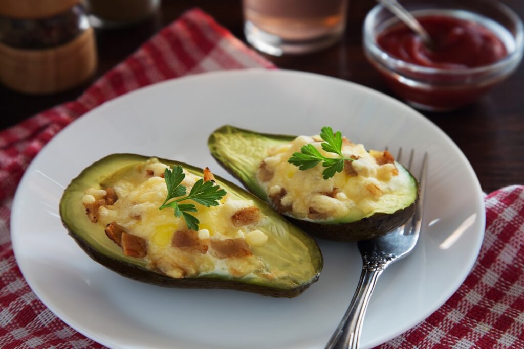 Two halves of avocado each generously stuffed with creamy tuna salad and garnished with green peas