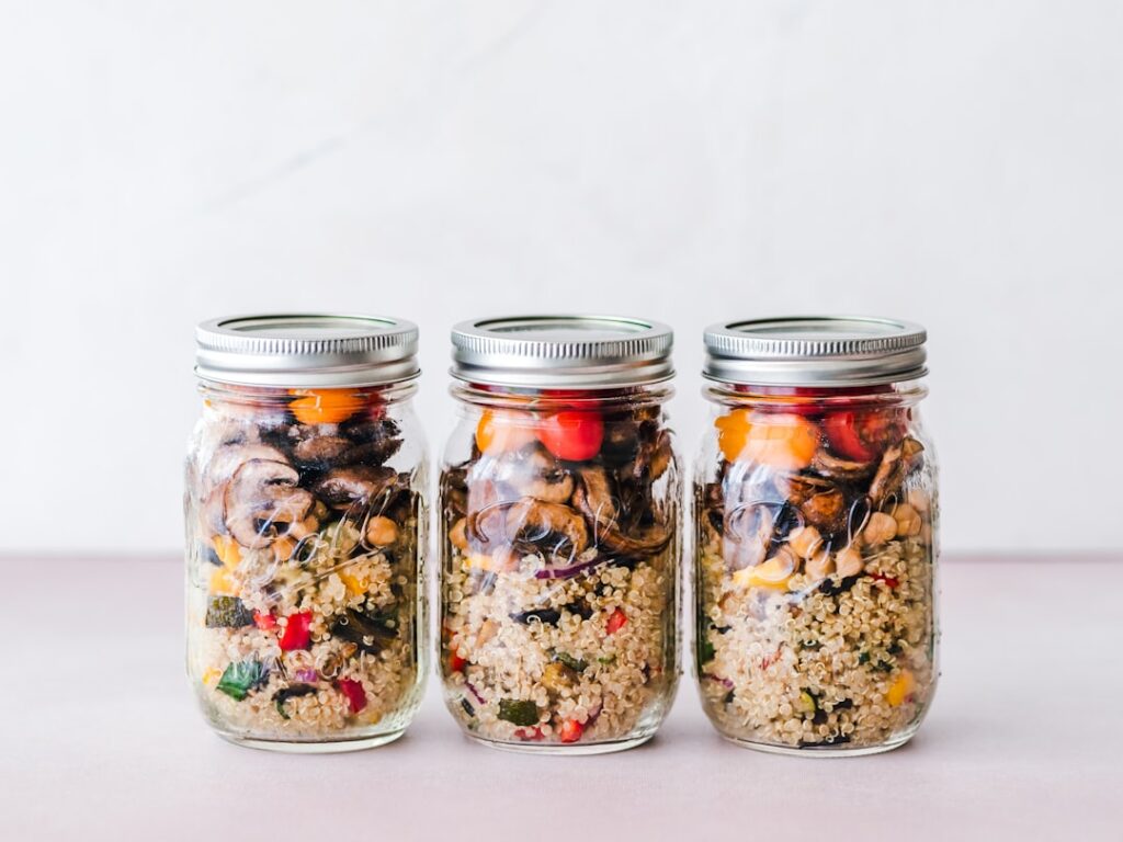 A clear mason jar filled with colorful layers of keto taco salad including seasoned ground beef cheese and lettuce