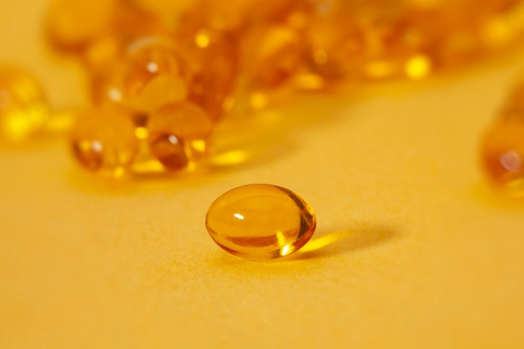 A vitamin E capsule being held between two fingers ready to be added to a skincare mixture