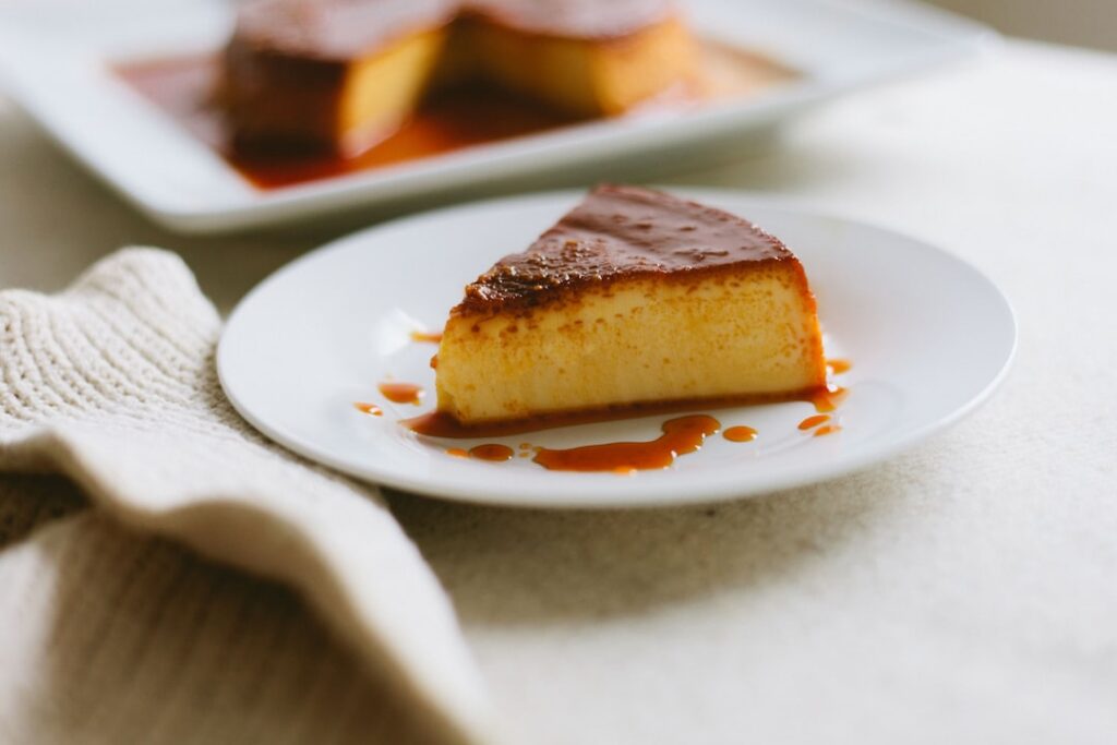A perfectly unmolded classic leche flan on a plate with golden caramel dripping down the sides ready to be sliced