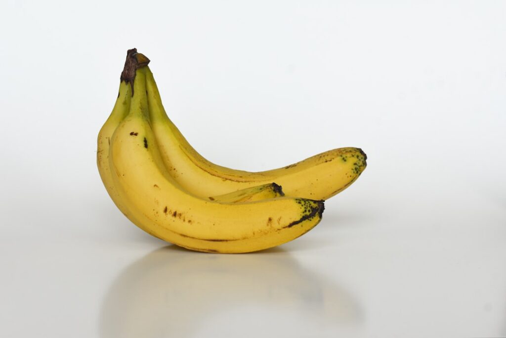 A close-up shot of perfectly ripe speckled bananas next to other vegan baking ingredients like flour plant milk and a bo
