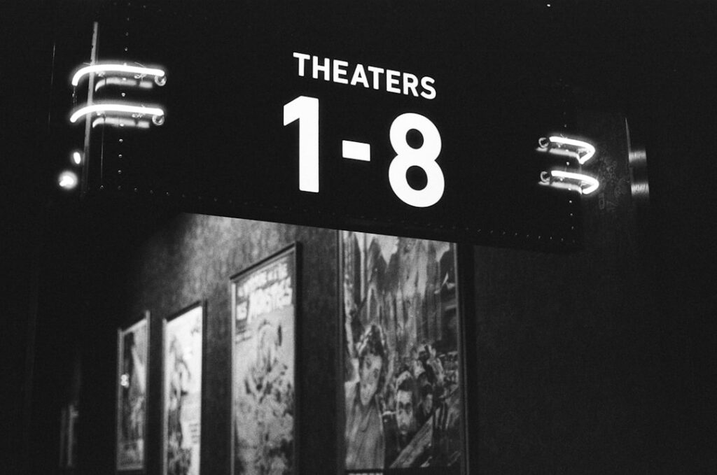 A vintage cinema marquee from the 1980s possibly showing classic movie titles with people gathered outside or a close-up