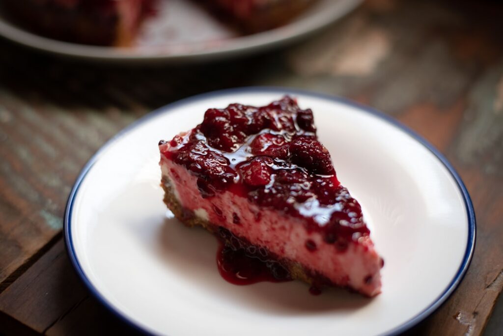 A beautifully layered vegan no-bake raspberry biscuit cake showing creamy white layers light brown biscuit layers and vi