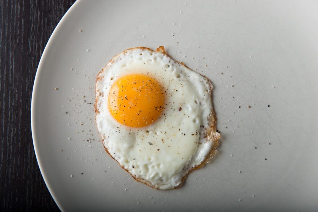 A close-up shot of a cracked egg showing a vibrant rich orange-yellow egg yolk in its shell symbolizing its nutritional 
