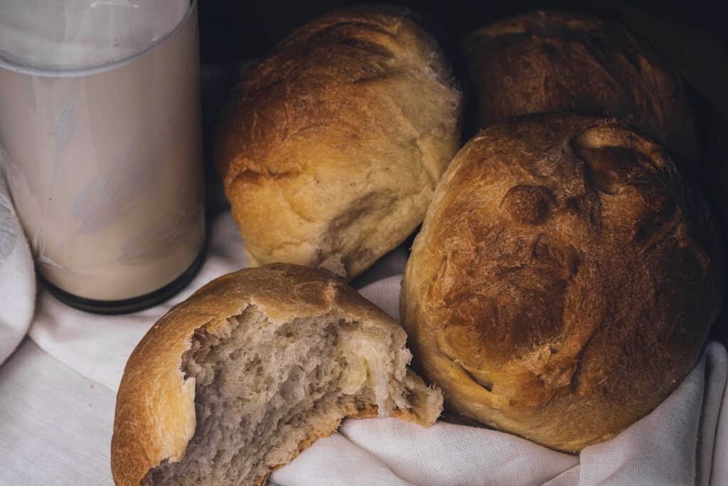 Close-up of freshly baked golden-brown vegan brioche rolls on a wooden board with some pulled apart to show the soft flu
