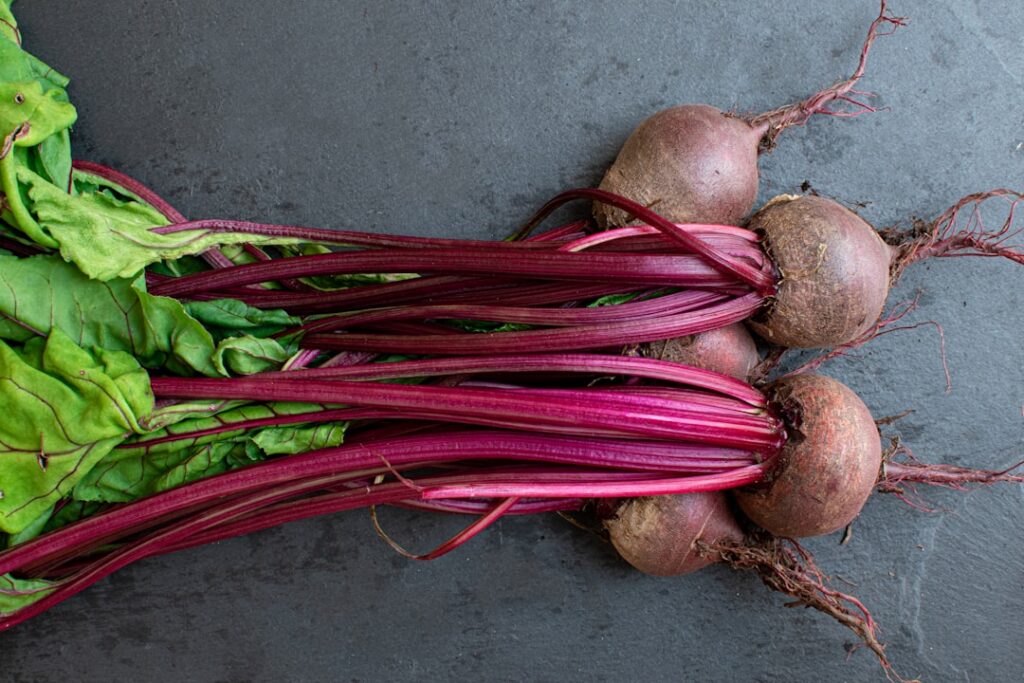 Close-up of fresh vibrant beetroots on a rustic wooden surface highlighting their rich color and earthy texture Some bee