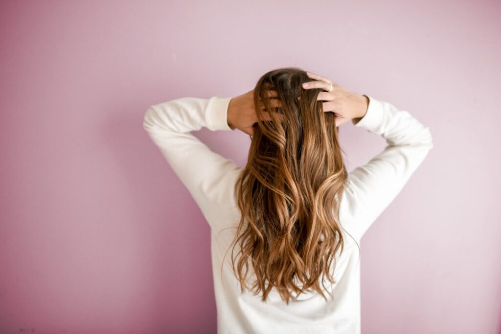 Person applying a dark hair mask to their roots with gloved hands