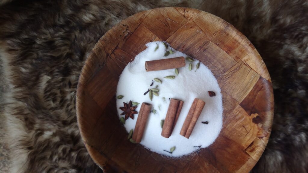 A close-up shot of a small jar of Vaseline a pile of ground clove powder and a small mixing bowl with a spoon showing th