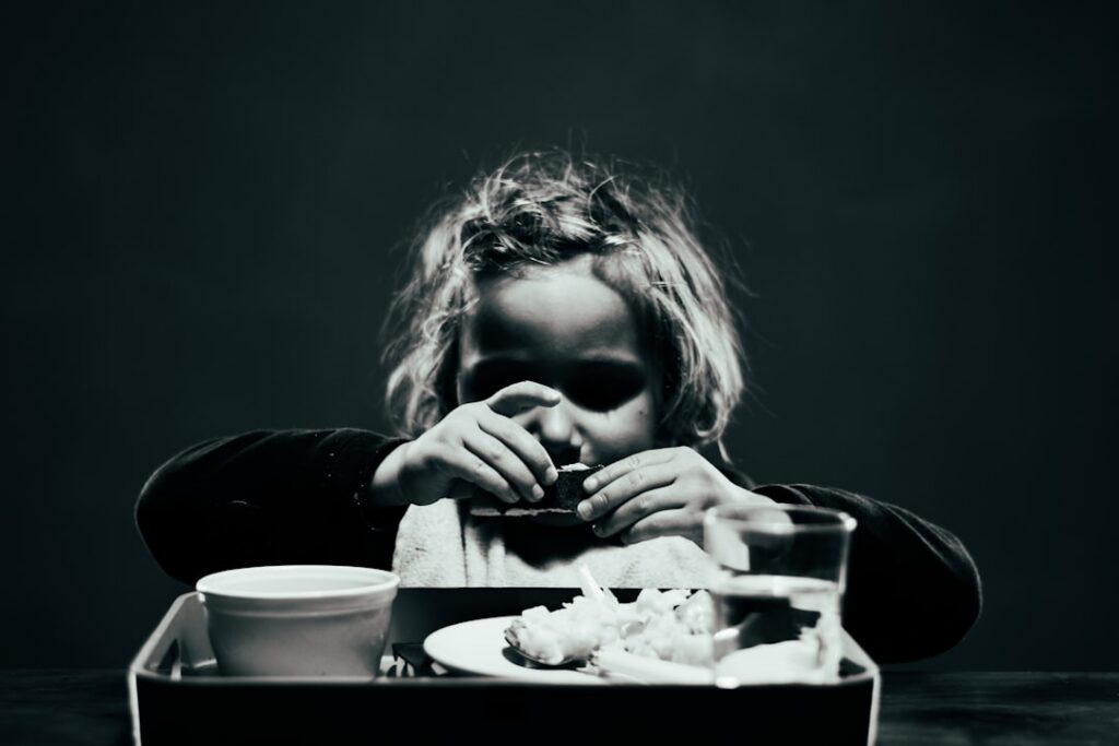 A person mindlessly snacking on highly processed foods like chips and candy while looking at a screen illustrating the e