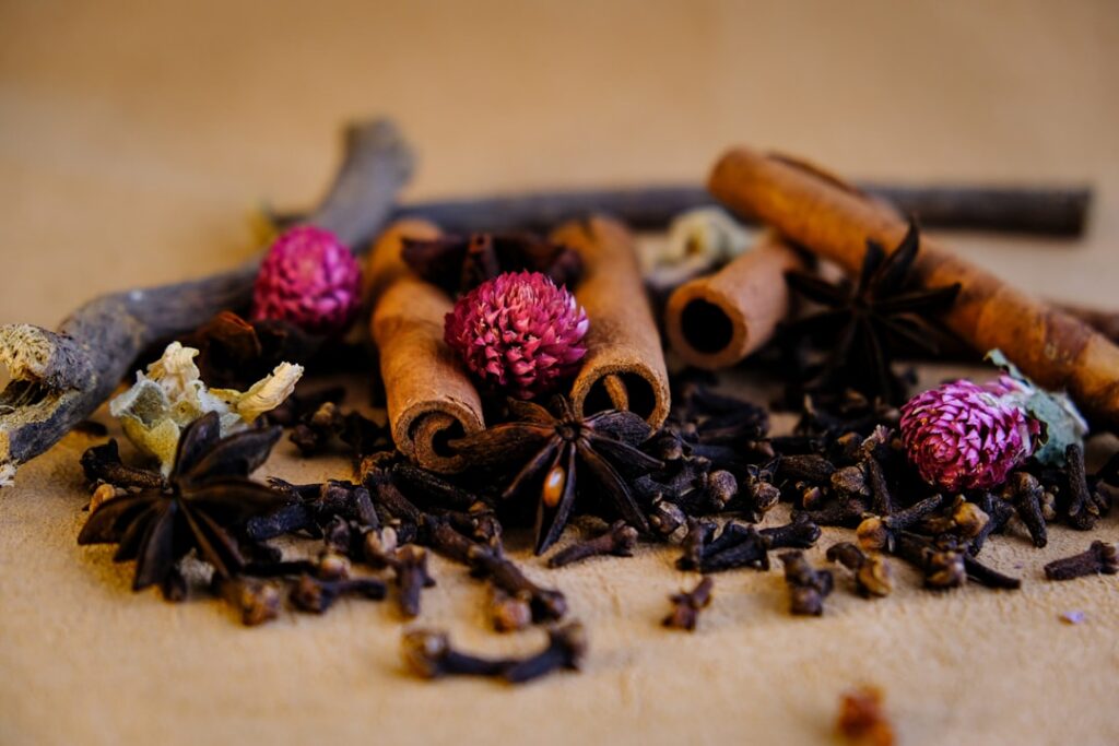 Close-up of dried turmeric root and whole cloves in separate piles with a small mortar and pestle in the background