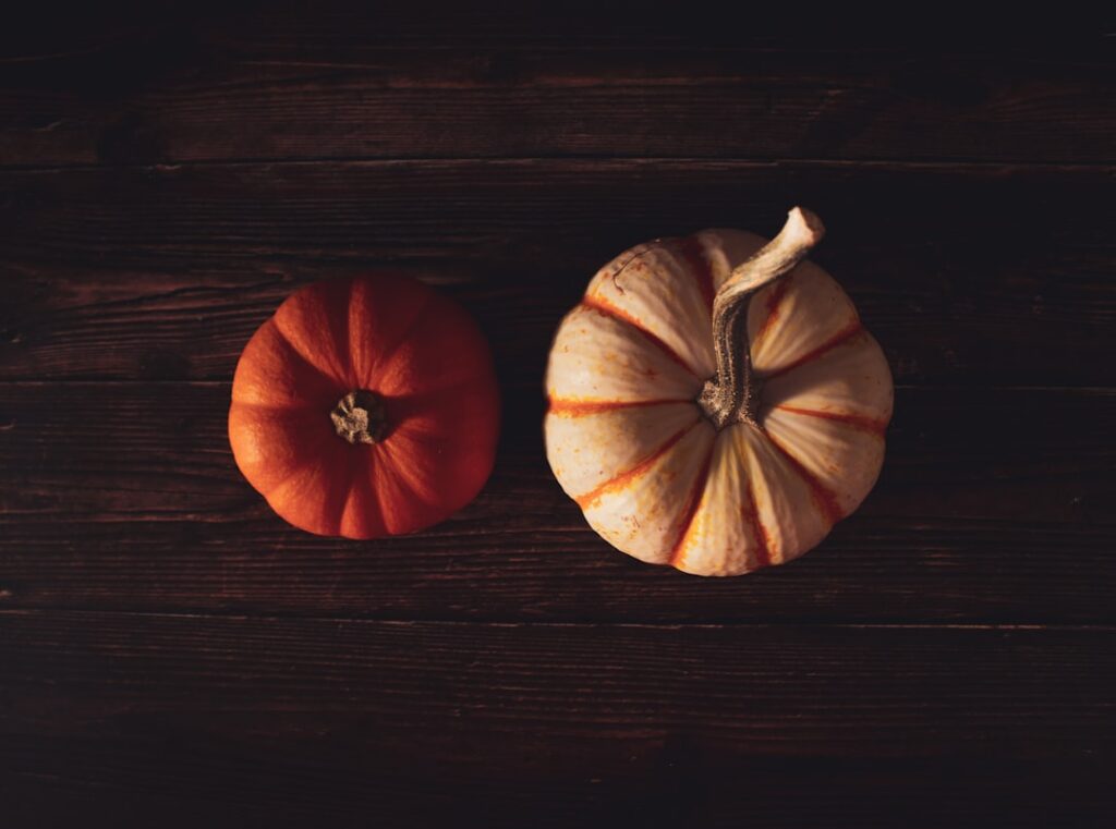 A side-by-side comparison of a whole potato and a whole pumpkin clearly showing their raw forms The background is clean 