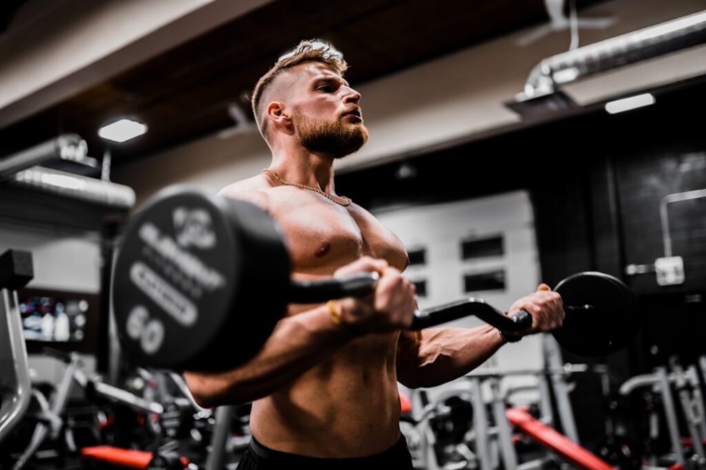 A person demonstrating proper bicep curl form with dumbbells elbows tucked close to the body smiling and focused in a gy