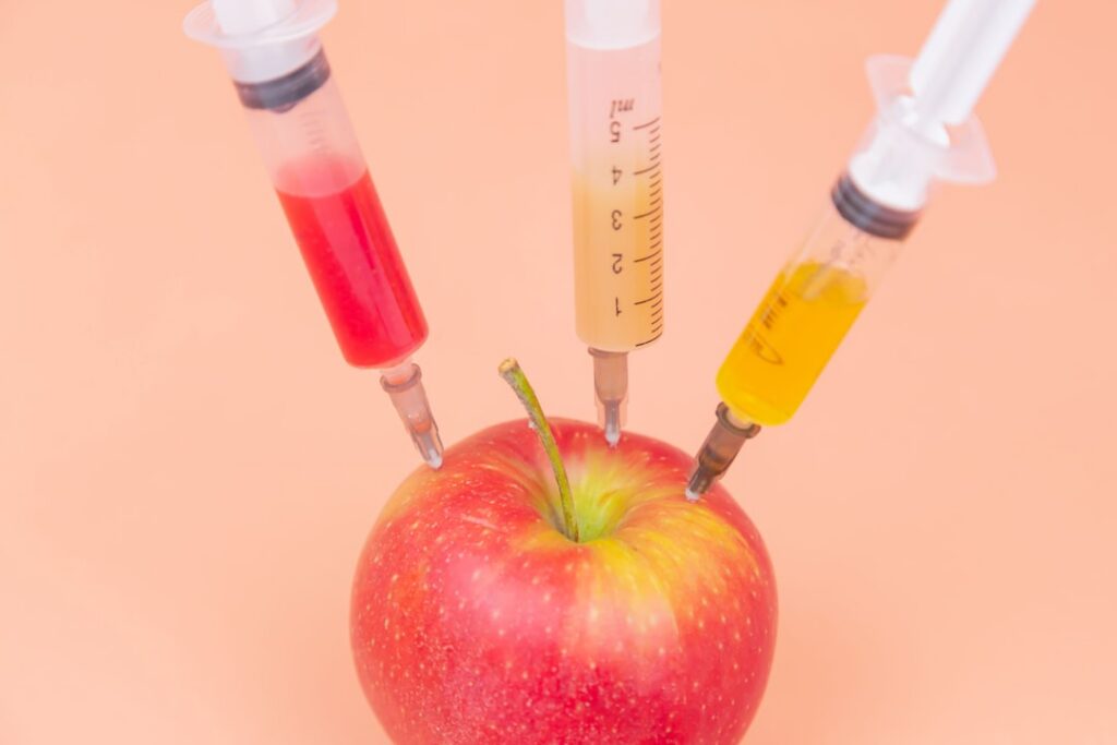 A glass with a fizzy drink possibly apple cider vinegar and baking soda next to skincare ingredients or fresh apples