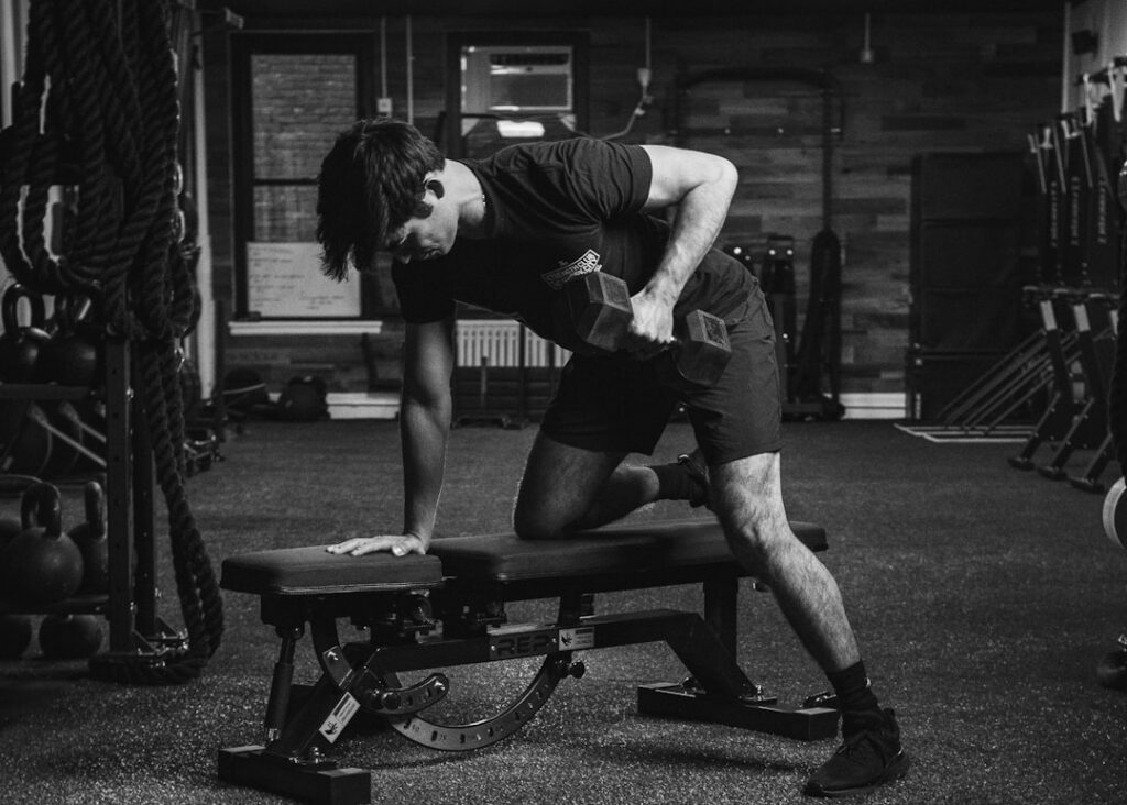 A person demonstrating a dumbbell pullover on a bench showing the dumbbell being lowered behind the head with controlled