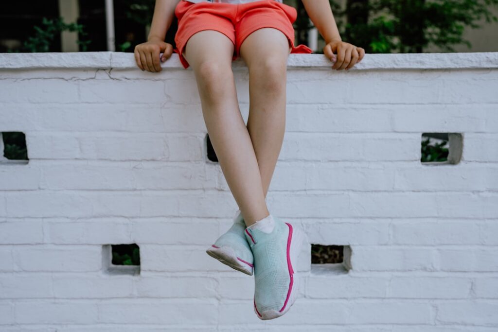 A person performing a wall sit against a plain wall showing thighs parallel to the ground