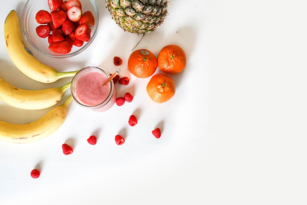A variety of smoothie ingredients laid out on a clean counter spinach banana a small bowl of chia seeds a carton of almo
