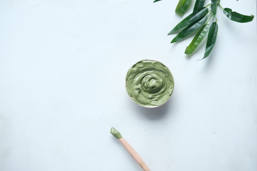 A beautiful close-up shot of a small bowl containing the homemade green gel with small containers of Vaseline Vitamin E 