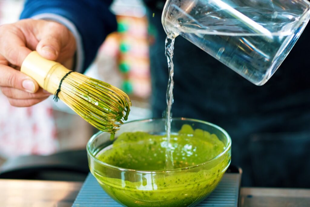 A close-up of three small bowls containing Vaseline honey and matcha powder arranged neatly on a wooden surface with som
