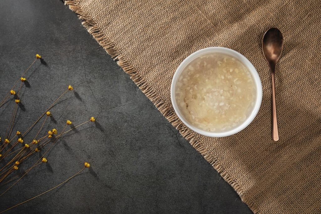 A small bowl containing a creamy white rice gel with a few grains of rice scattered around the bowl on a light backgroun