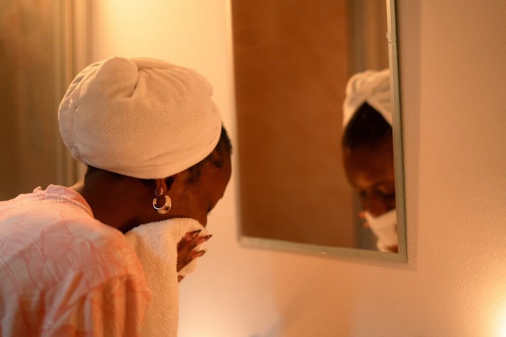A woman gently patting her clean glowing face with a soft towel after rinsing off a face mask Her skin looks fresh smoot