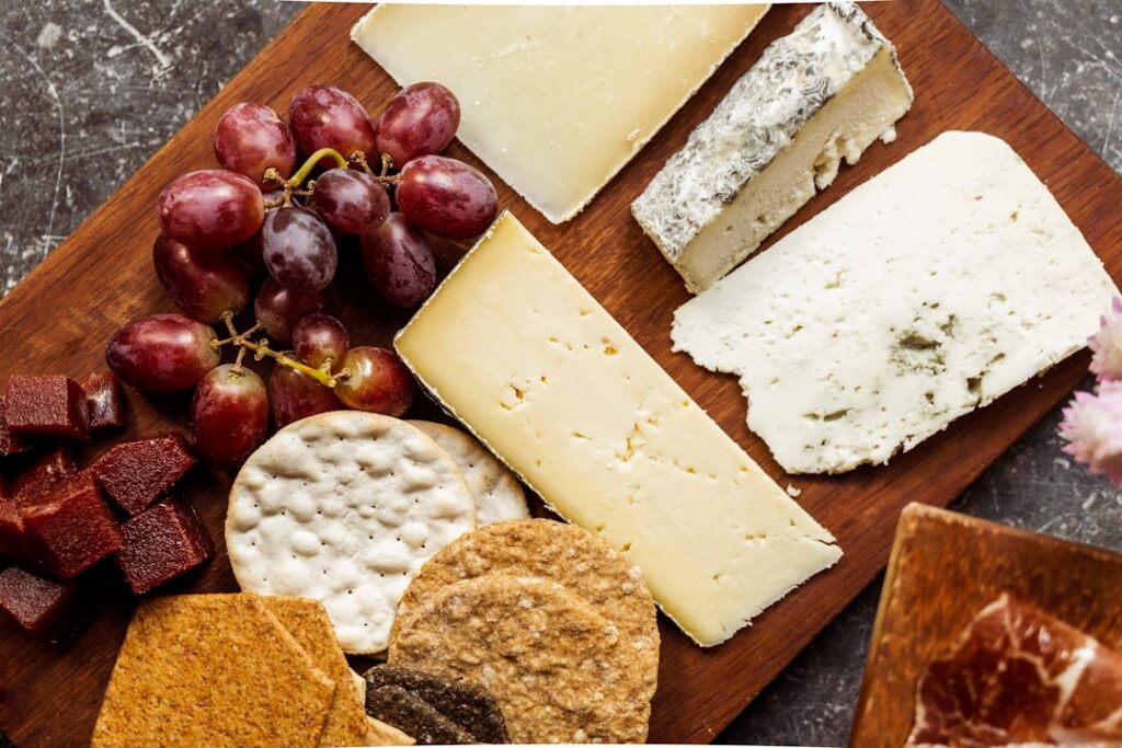 A beautiful cheese board featuring various types of cheese Brie Cheddar Goat cheese grapes crackers and honey arranged a