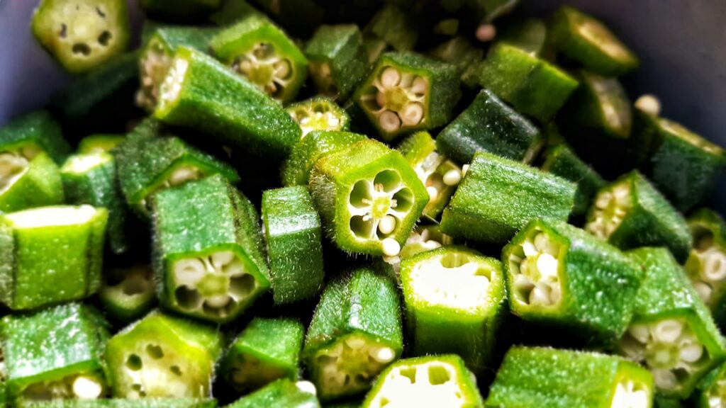 Fresh green okra pods alongside a clear bowl of translucent okra gel with a spoon