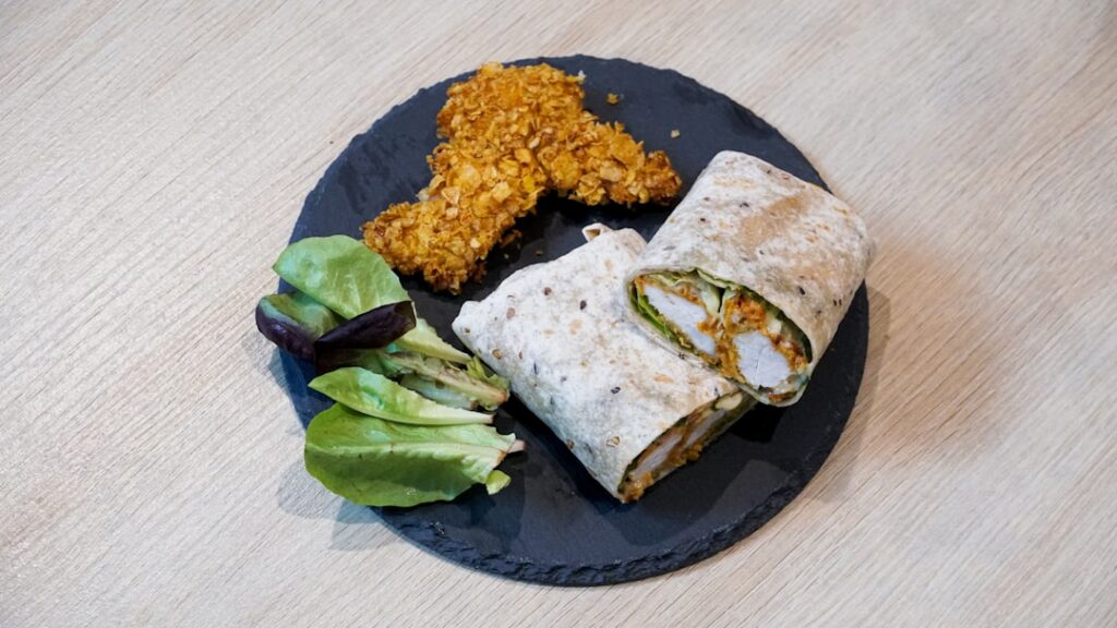 A perfectly made crispy vegan wrap cut in half to show the vibrant interior of vegan chicken fresh green lettuce colorfu