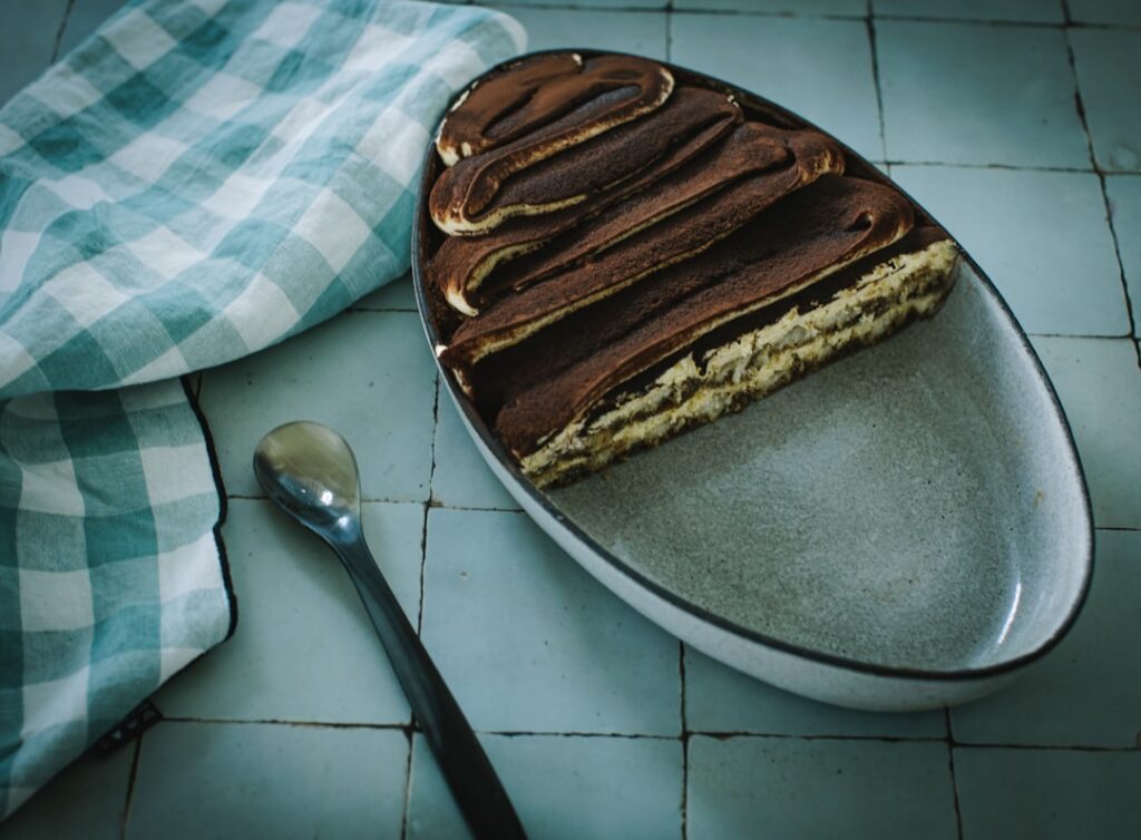 A beautifully layered vegan tiramisu dusted with cocoa powder served in a glass dish or individual servings The layers o