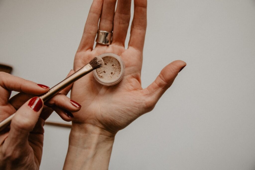 Close-up of hands gently mixing natural ingredients like clay water and essential oils in a small bowl with various natu