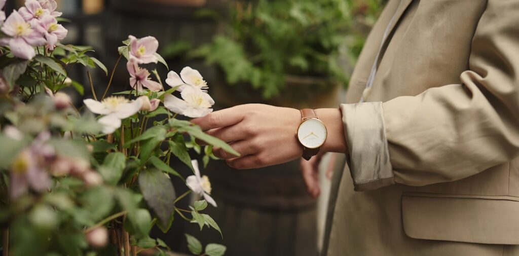 A close-up of a gardener s hands tending to a flowering plant perhaps pruning or watering with a blurred background of a