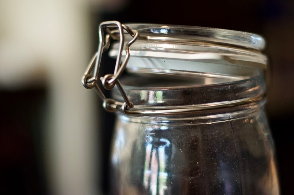 Sliced okra pods soaking in a glass jar of water possibly with a lemon slice in a kitchen setting