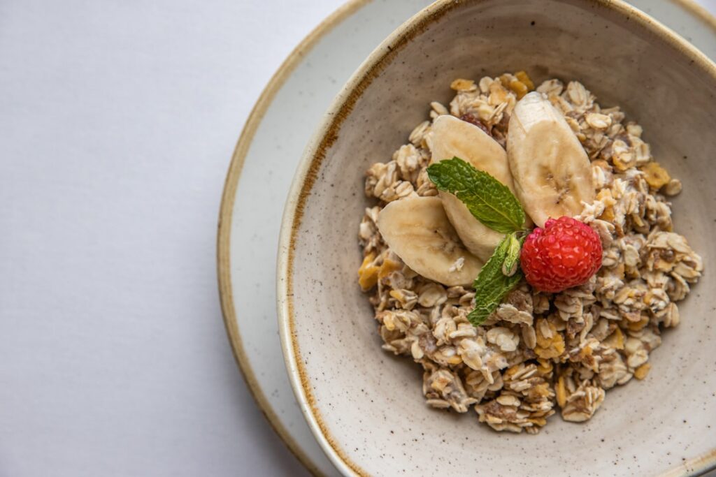 A warm bowl of quick oatmeal garnished with sliced bananas peanut butter and cinnamon with a spoon